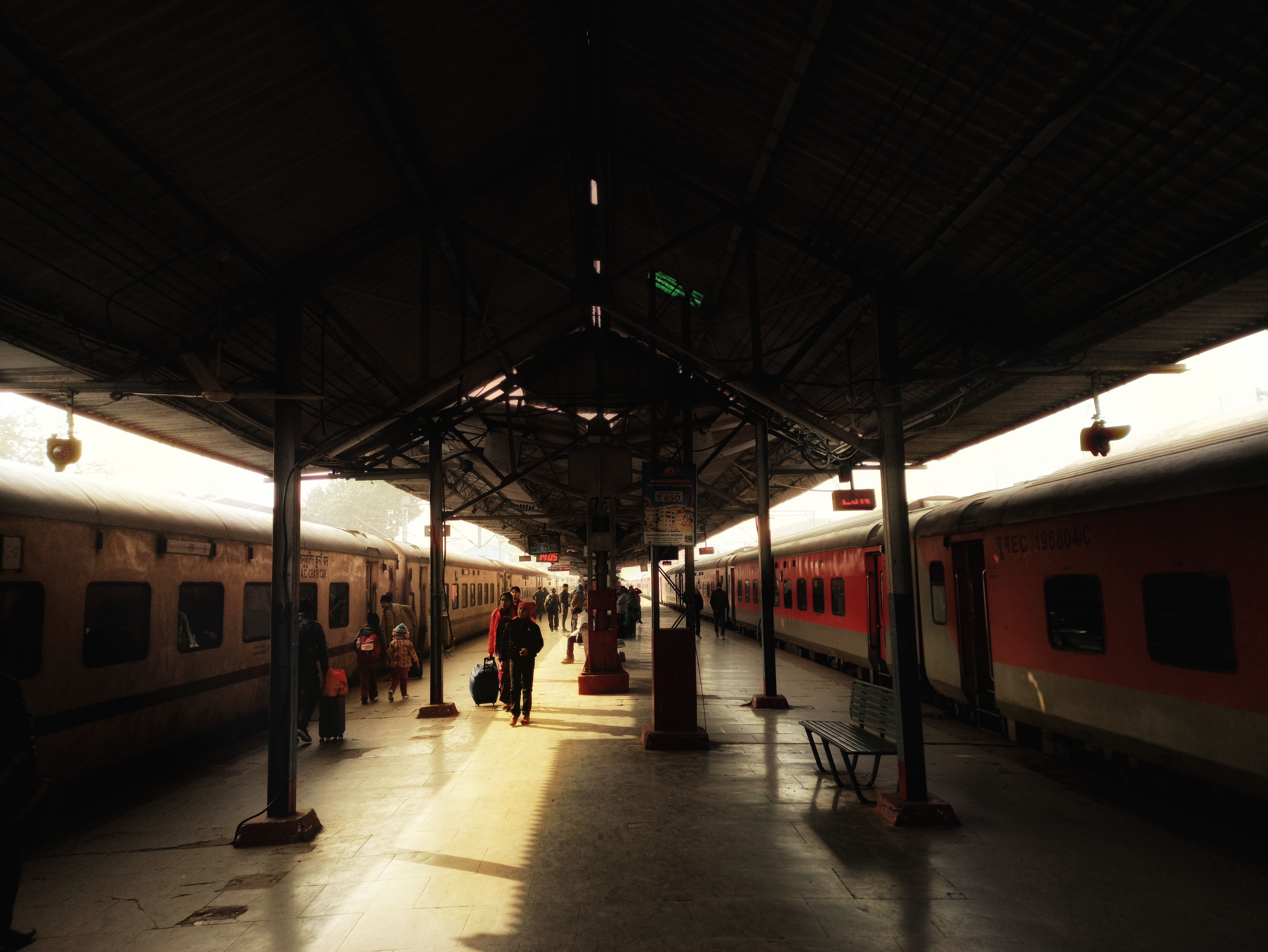 Busy Indian railway platform at dusk, with a passenger holding a paper ticket